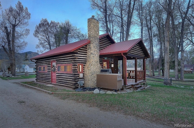 view of home's exterior featuring log siding, a chimney, and metal roof