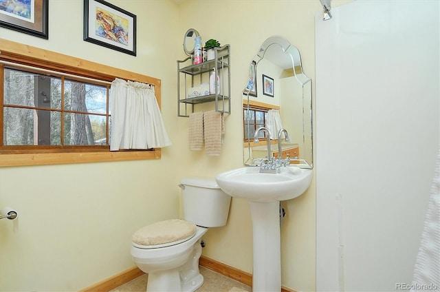 half bathroom featuring baseboards and toilet