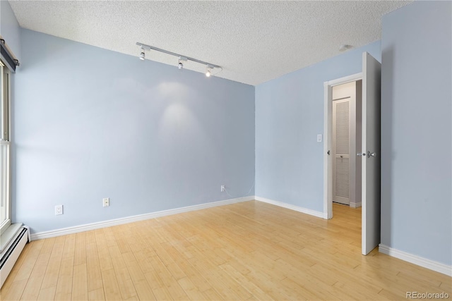 850 W Moorhead Cir Unit 3L, Boulder, CO 80305 - empty room featuring baseboard heating, light wood-style floors, a textured ceiling, and rail lighting