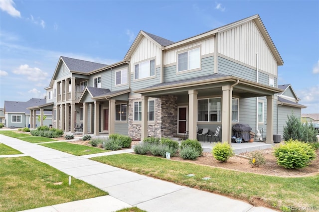 2561 Stage Coach Dr Unit B, Milliken, CO 80543 - view of front of property featuring board and batten siding, a front lawn, cooling unit, stone siding, and a patio