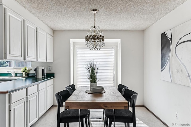 dining area with baseboards, light carpet, a notable chandelier, and a textured ceiling