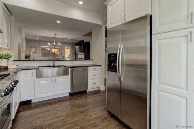 kitchen with kitchen peninsula, appliances with stainless steel finishes, sink, dark hardwood / wood-style floors, and white cabinetry