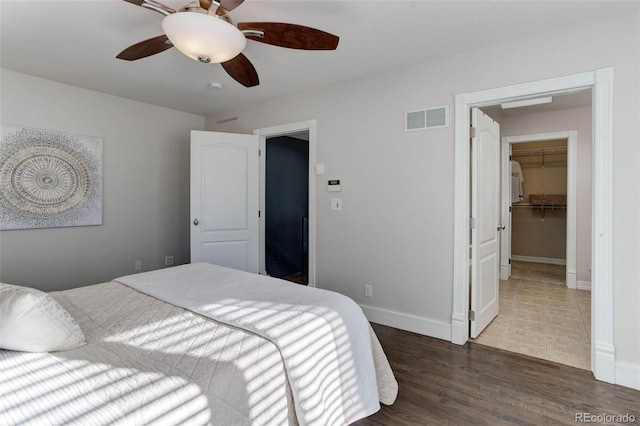 bedroom with dark wood-type flooring, ceiling fan, a closet, and a spacious closet