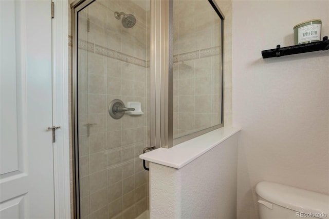 bathroom featuring a shower with shower door and toilet