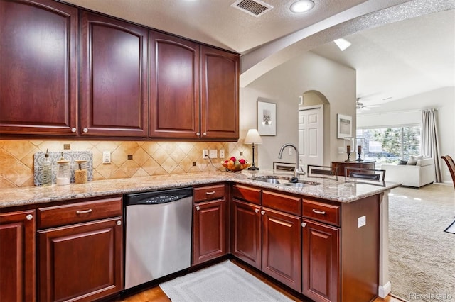 kitchen featuring sink, stainless steel dishwasher, light colored carpet, light stone counters, and kitchen peninsula