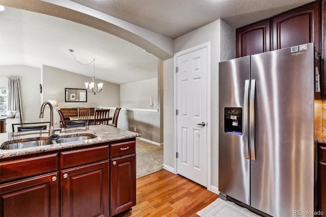 kitchen featuring pendant lighting, lofted ceiling, sink, stainless steel fridge with ice dispenser, and light wood-type flooring