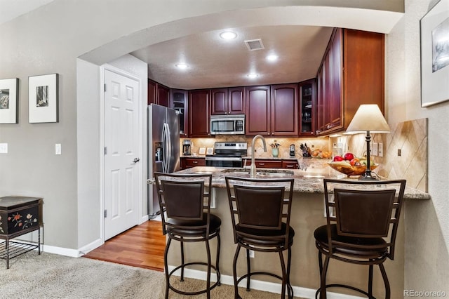 kitchen featuring decorative backsplash, a breakfast bar area, stainless steel appliances, and kitchen peninsula