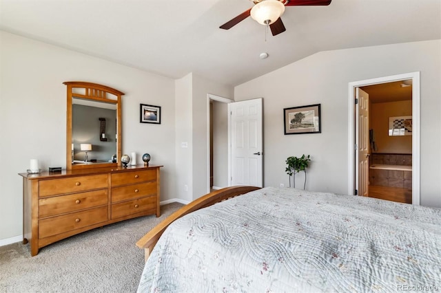 bedroom featuring ceiling fan, ensuite bathroom, vaulted ceiling, and light carpet