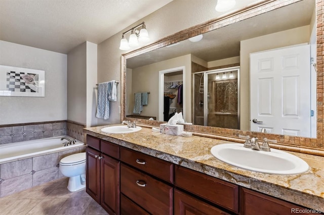 full bathroom featuring independent shower and bath, tile patterned flooring, vanity, toilet, and a textured ceiling