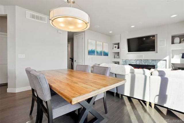 dining area featuring built in shelves and dark hardwood / wood-style floors