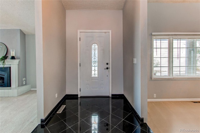 entryway featuring a tiled fireplace and a textured ceiling