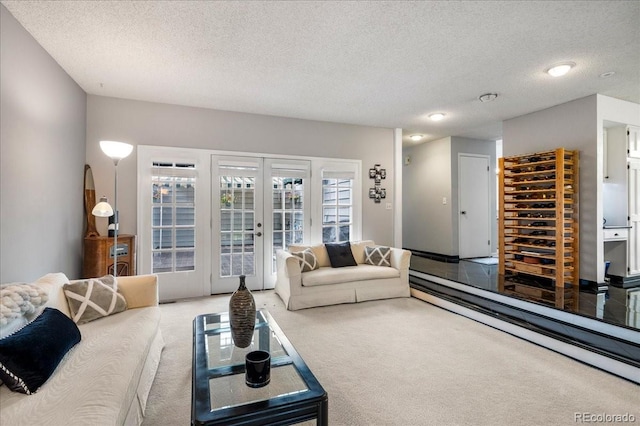 carpeted living room with french doors and a textured ceiling