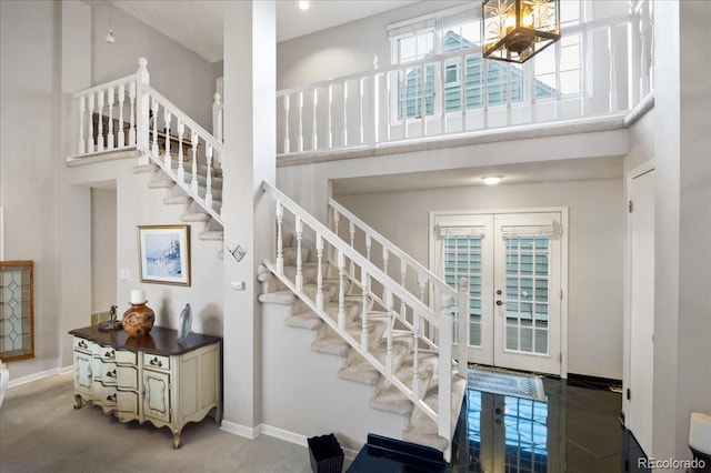 stairs featuring a notable chandelier, french doors, and a high ceiling