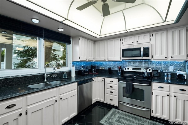 kitchen with sink, appliances with stainless steel finishes, dark stone counters, and white cabinetry