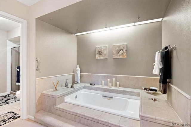 bathroom featuring tiled tub, toilet, and tile patterned floors