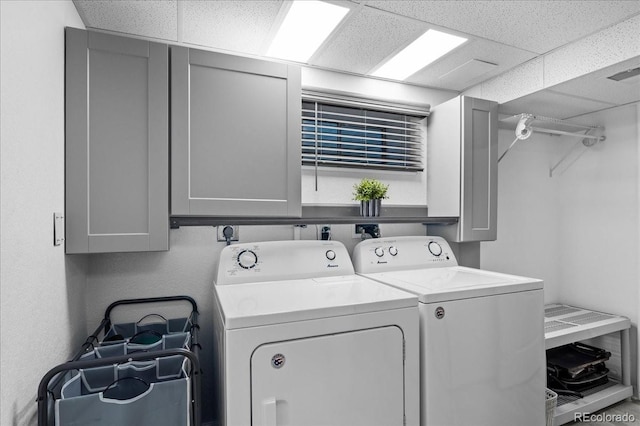 clothes washing area featuring washing machine and clothes dryer and cabinets