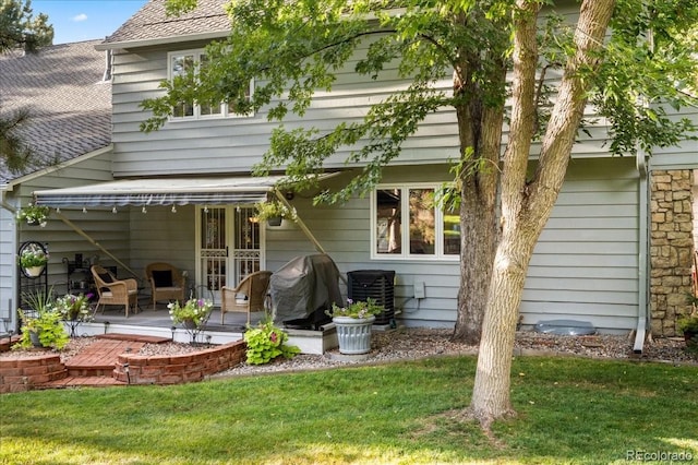 back of property featuring cooling unit and a lawn