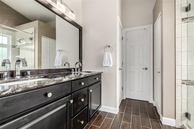 8410 S Oak St, Littleton, CO 80127 - full bathroom featuring double vanity, a shower stall, wood finish floors, and a closet