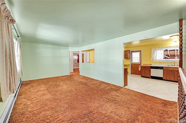 carpeted empty room featuring a baseboard radiator and sink