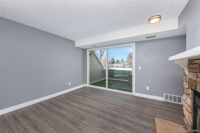 unfurnished living room with dark wood-style floors, a fireplace, visible vents, and baseboards