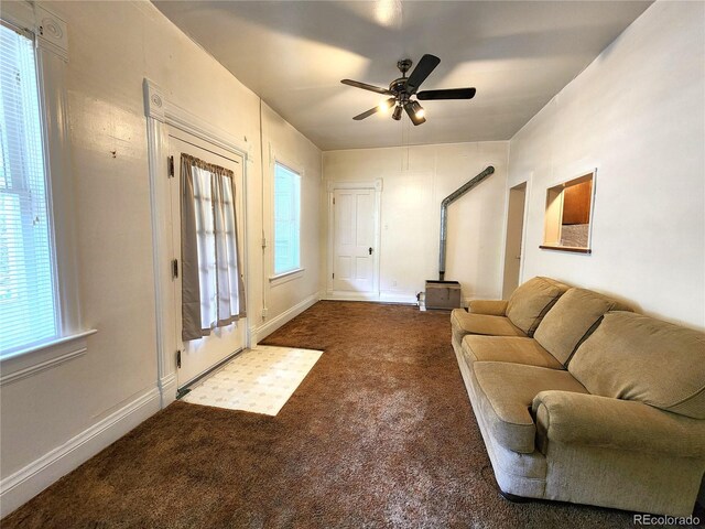 carpeted living room featuring ceiling fan and a wood stove