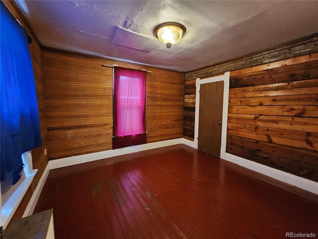 spare room featuring wood walls and hardwood / wood-style flooring