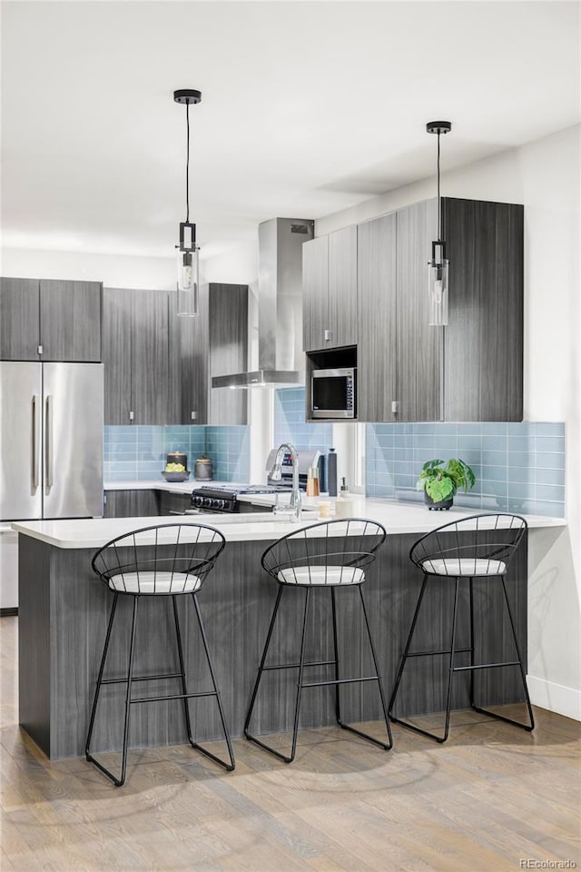 2435 S High St, Denver, CO 80210 - kitchen with stainless steel appliances, wall chimney exhaust hood, modern cabinets, a breakfast bar area, and decorative backsplash