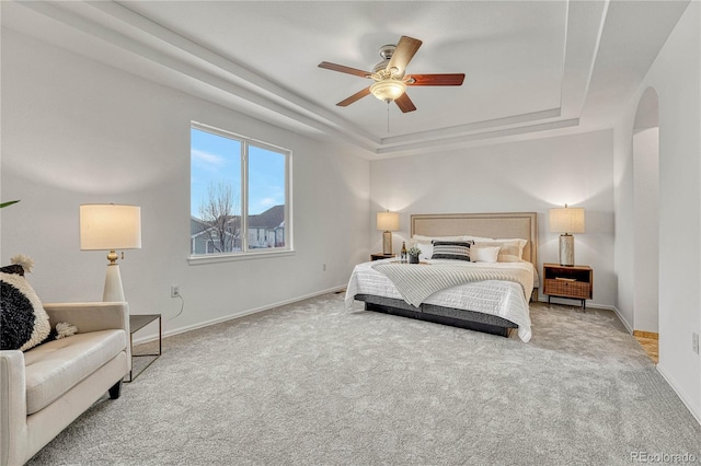 carpeted bedroom featuring a tray ceiling and ceiling fan