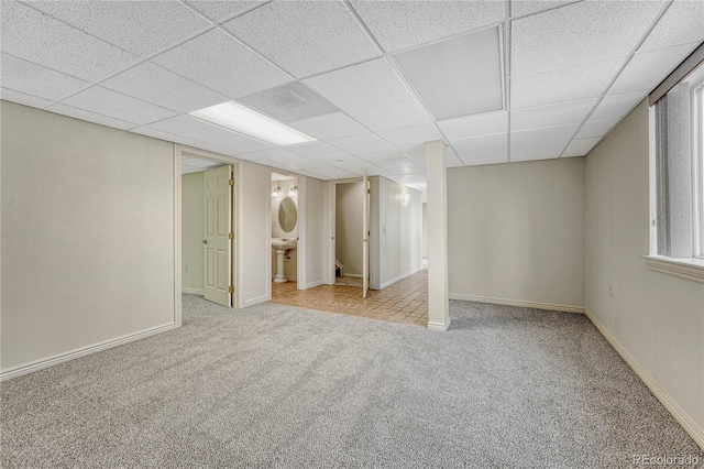 basement with a paneled ceiling and light carpet