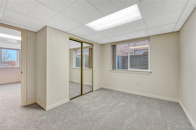 unfurnished bedroom featuring a closet, carpet, and a drop ceiling