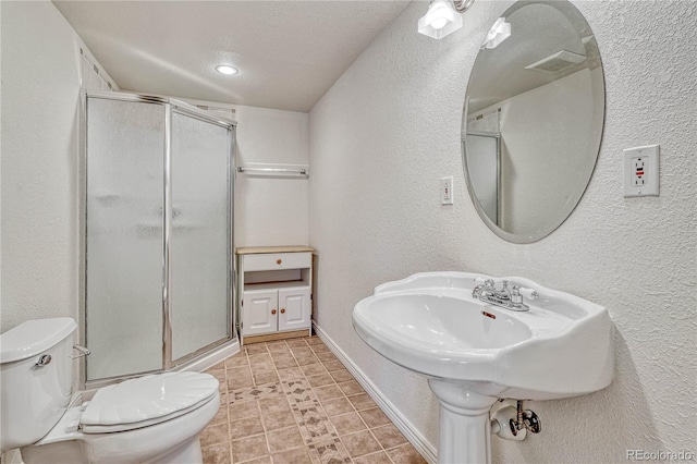 bathroom featuring toilet, a shower with shower door, and a textured ceiling