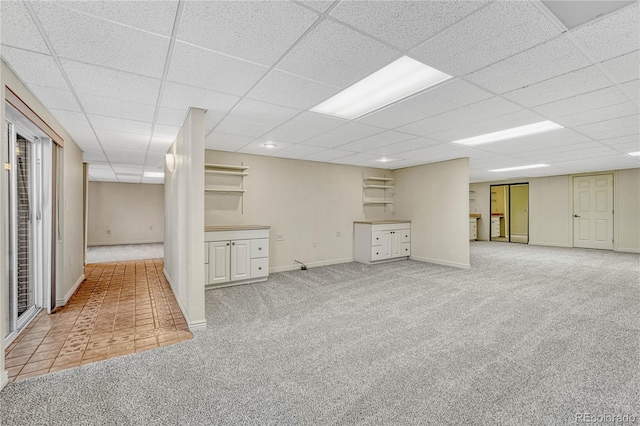 basement featuring a drop ceiling and carpet