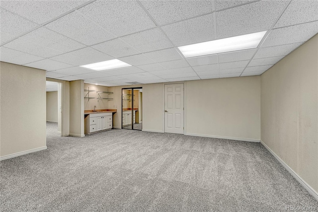 basement with carpet, a drop ceiling, and sink