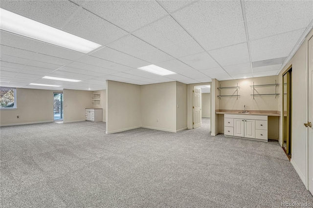 basement with a paneled ceiling and light carpet