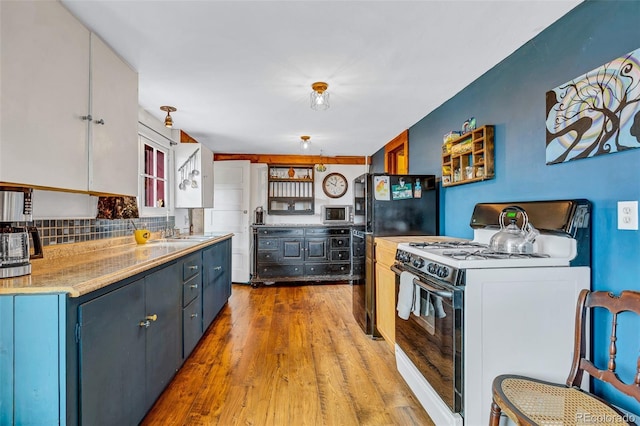 500 Fourth St, Fairplay, CO 80440 - kitchen with white gas range oven, light wood-style floors, decorative backsplash, stainless steel microwave, and freestanding refrigerator