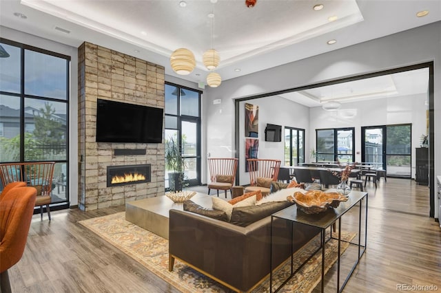 12940 Brier Ct, Firestone, CO 80504 - living room featuring a tray ceiling, wood finished floors, a fireplace, and recessed lighting