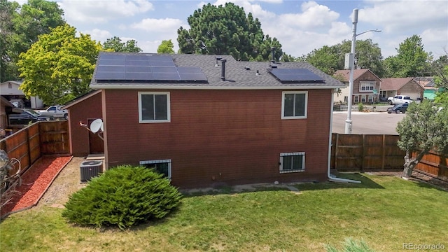4396 Dearborn St, Denver, CO 80239 - back of property featuring roof mounted solar panels, a fenced backyard, and a shingled roof