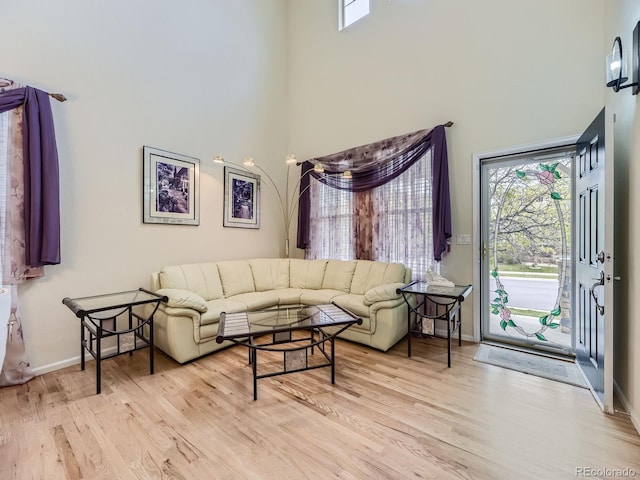 living room with a towering ceiling and light wood-type flooring