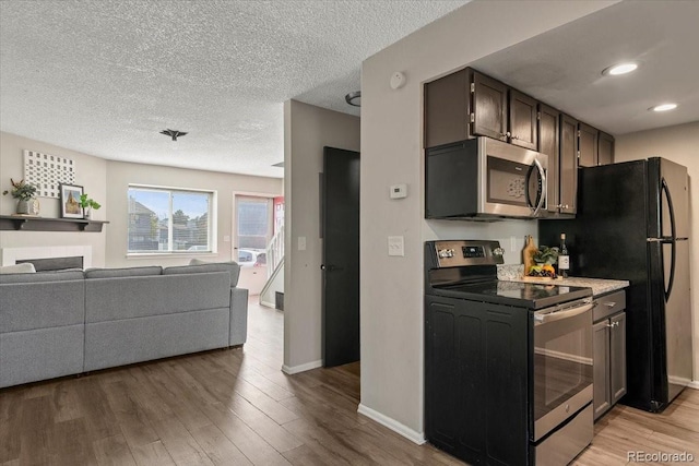 kitchen featuring light hardwood / wood-style floors, a textured ceiling, and stainless steel appliances