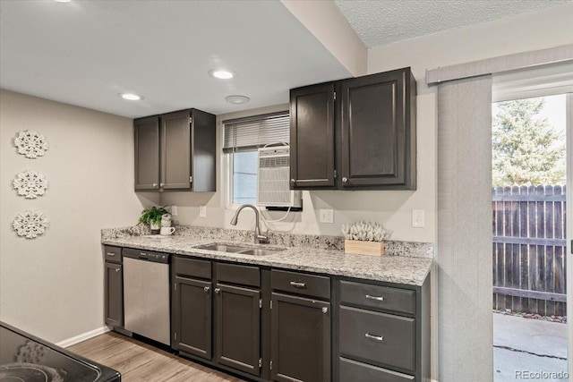 kitchen with stainless steel dishwasher, sink, light stone counters, and light wood-type flooring