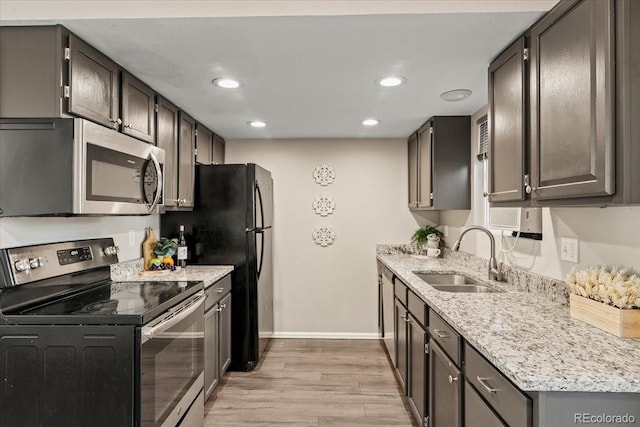 kitchen with light hardwood / wood-style floors, stainless steel appliances, sink, and light stone counters