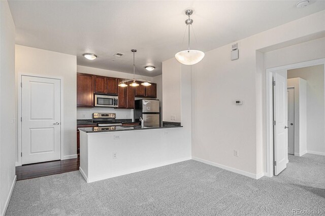 4100 Albion St Unit 617, Denver, CO 80216 - kitchen with stainless steel appliances, light colored carpet, dark countertops, and hanging light fixtures