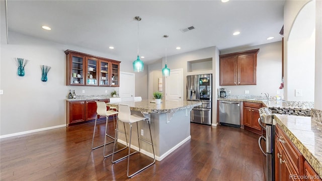18009 E 47th Pl, Denver, CO 80249 - kitchen featuring appliances with stainless steel finishes, a breakfast bar, dark wood finished floors, a kitchen island, and glass insert cabinets