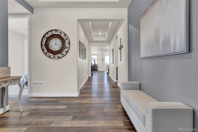 hall featuring a raised ceiling, baseboards, wood finished floors, and visible vents