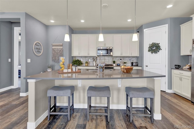 kitchen featuring backsplash, dark wood-style flooring, a sink, white cabinets, and stainless steel microwave