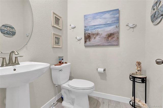 bathroom with toilet, baseboards, and a sink