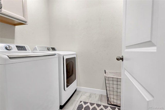 laundry area with cabinet space, independent washer and dryer, and baseboards