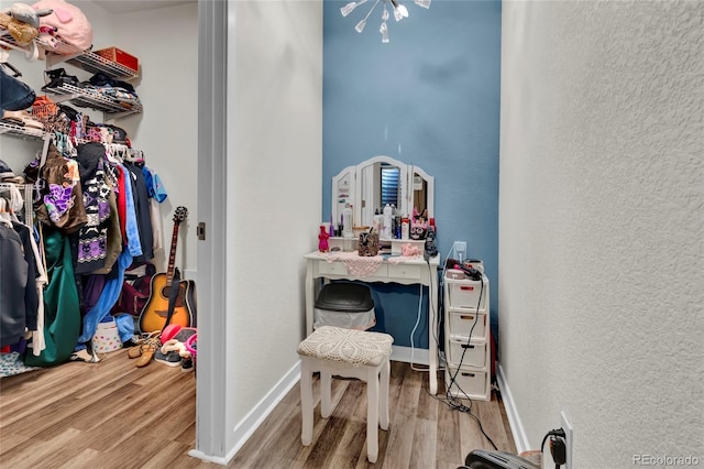 interior space featuring baseboards, a textured wall, and wood finished floors