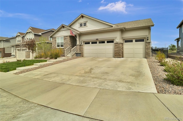 craftsman-style house featuring fence, an attached garage, driveway, and stone siding