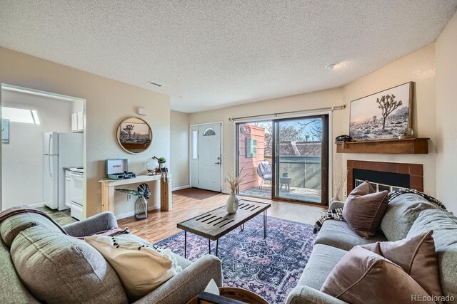 3050 W 32nd Ave Unit 202C, Denver, CO 80211 - living room with light wood finished floors, a textured ceiling, a tile fireplace, and baseboards